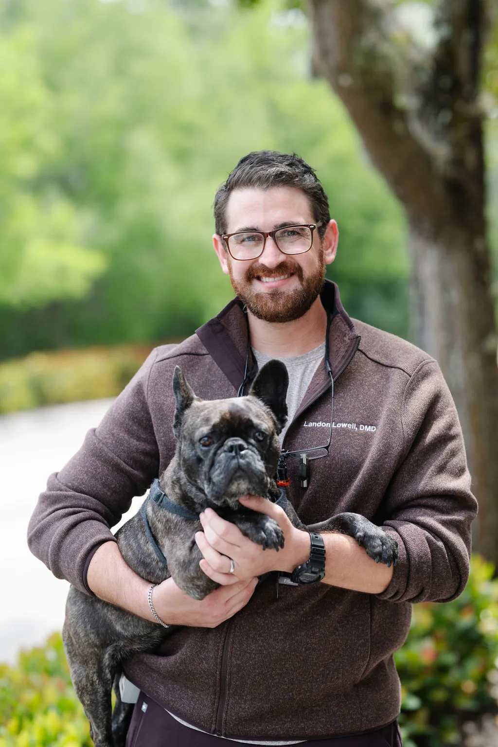 Dr. Lowell with His Dog – Suncoast Dental Center - suncoast dental center reviews Dr. Lowell smiles while holding his French Bulldog outdoors, reflecting his friendly personality and love for animals outside the dental office. - suncoast dental center reviews