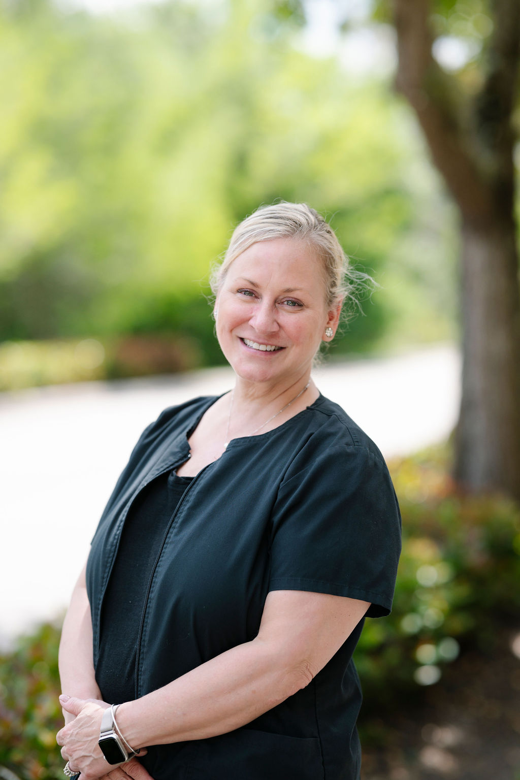 Tracy – Dedicated Dental Hygienist at Suncoast Dental Center - suncoast dental center reviews Tracy, a friendly dental hygienist, stands confidently outdoors in her uniform, reflecting the professionalism and patient-focused care of Suncoast Dental Center. - suncoast dental center reviews