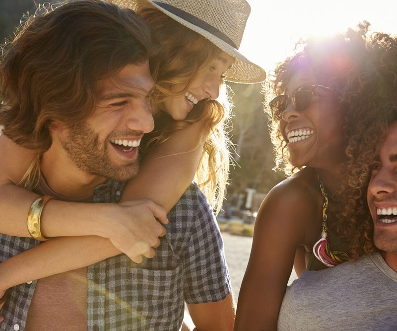 A group of friends share a joyful moment under the sun, symbolizing confidence and happiness that comes with a healthy smile made possible through mobile dentistry - mobile dentures