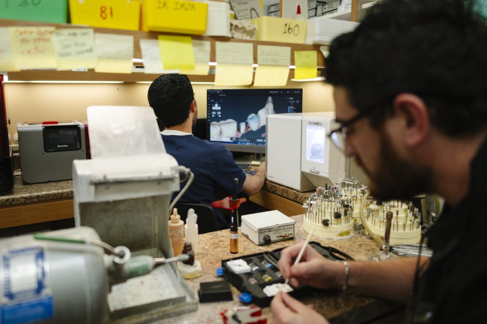 Dental Lab Technician Crafting Restoration – Dentist in Naples, FL A dental technician works on custom restorations at a lab bench, focusing on precision and detail to create high-quality dental prosthetics – Dentist in Naples, FL